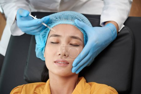 Foto de Mujer asiática joven recibiendo tratamiento antiarrugas en la frente, vista desde arriba - Imagen libre de derechos