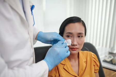 Téléchargez les photos : Chirurgien plastique décollant patch pour vérifier le nez du patient après Rhinoplastie - en image libre de droit