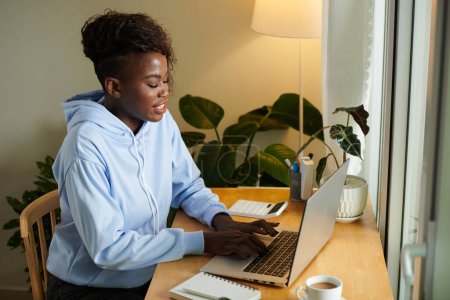 Photo for Young Black woman working on laptop at her desk in home office - Royalty Free Image