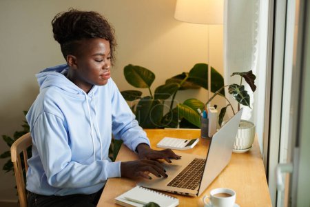 Foto de Joven mujer de negocios con capucha azul claro trabajando en el portátil en su escritorio - Imagen libre de derechos