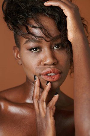 Téléchargez les photos : Visage de jeune femme noire sensuelle touchant la tête et regardant la caméra - en image libre de droit