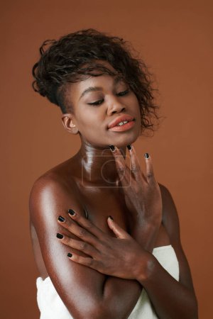Téléchargez les photos : Portrait de jolie jeune femme noire touchant sa peau propre et lisse après le bain - en image libre de droit