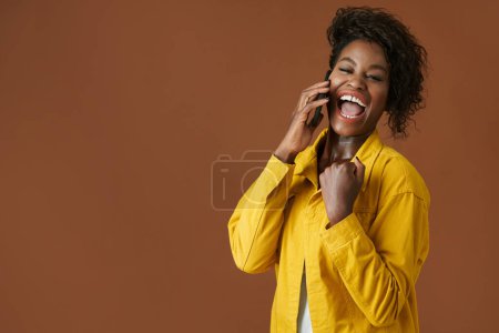 Téléchargez les photos : Portrait de jeune femme noire excitée faisant geste de pompe poing lors de la réception de bonnes nouvelles sur smartphone - en image libre de droit