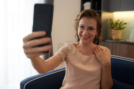 Téléchargez les photos : Heureuse femme d'âge moyen en lunettes prenant selfie sur smartphone - en image libre de droit