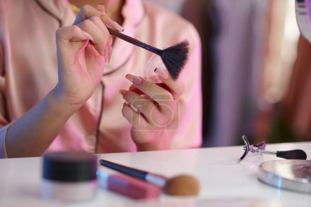 Foto de Manicura manos aplicando polvo facial en el cepillo de maquillaje - Imagen libre de derechos