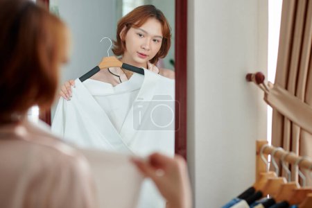 Photo for Transgender woman trying on white blouse in front of mirror - Royalty Free Image