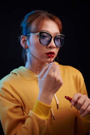 Téléchargez les photos : Transgenre femme en lunettes de soleil appliquant rouge à lèvres - en image libre de droit
