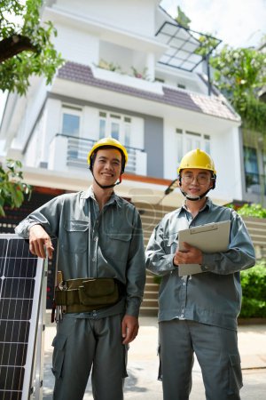 Téléchargez les photos : Entrepreneurs en uniforme gris prêts à installer un panneau solaire - en image libre de droit