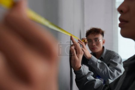 Téléchargez les photos : Travailleurs mesurant le mur de la maison peinte avant peinture - en image libre de droit