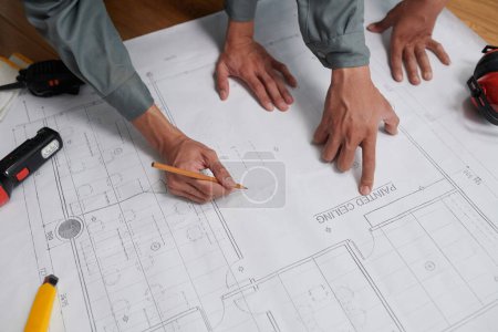 Téléchargez les photos : Mains de constructeurs vérifiant le plan de construction avant de commencer les travaux, vue d'en haut - en image libre de droit