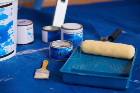 Foto de Latas con pintura azul, cepillos y rodillos en el suelo de la casa - Imagen libre de derechos