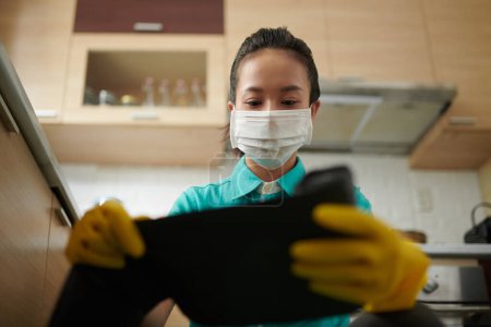 Foto de Trabajador de servicio de limpieza con máscara médica al cambiar la bolsa de basura - Imagen libre de derechos