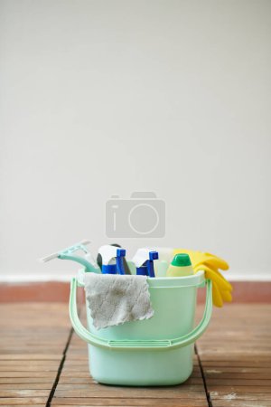 Foto de Cubo lleno de detergentes, aerosoles de limpieza, paños de microfibra y rascador de plástico - Imagen libre de derechos