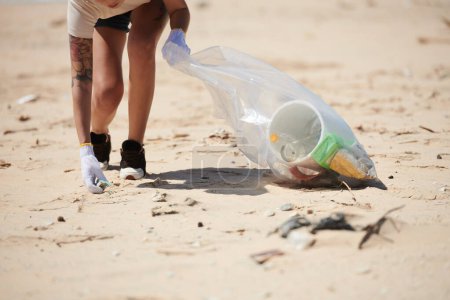 Téléchargez les photos : Image recadrée de femmes bénévoles nettoyant la plage des déchets plastiques - en image libre de droit