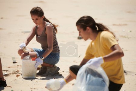 Téléchargez les photos : Jeune femme participant au nettoyage de la plage le jour de la Terre - en image libre de droit