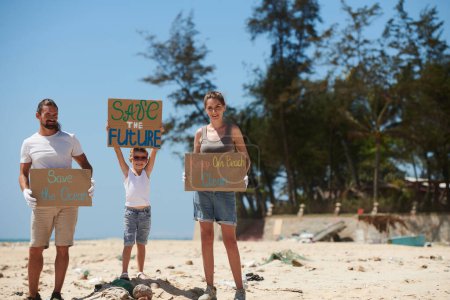 Photo for Happy family with handmade placards standing on dirty beach and asking to save the ocean - Royalty Free Image