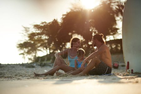 Téléchargez les photos : Bonne mère, père et petite fille reposant sur la plage de sable - en image libre de droit