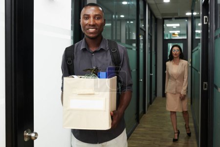 Téléchargez les photos : Portrait d'homme noir souriant heureux apportant boîte en carton de biens au bureau de l'entreprise - en image libre de droit