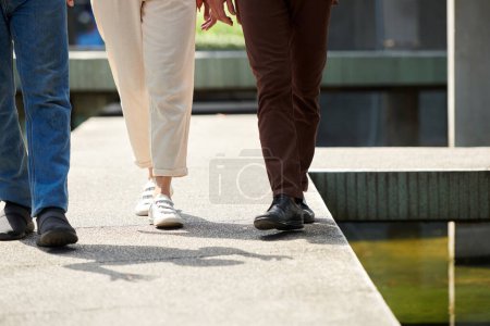 Photo for Cropped imaged male and female friends walking outdoors on sunny day - Royalty Free Image