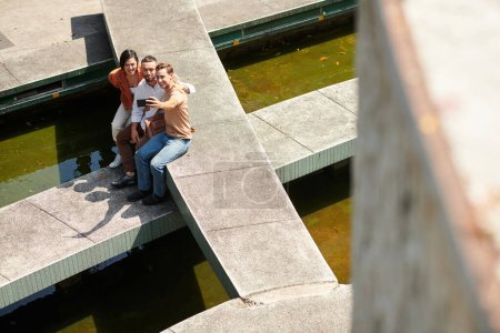 Téléchargez les photos : Câlin amis prendre selfie pour les médias sociaux lors du repos dans le parc de la ville - en image libre de droit