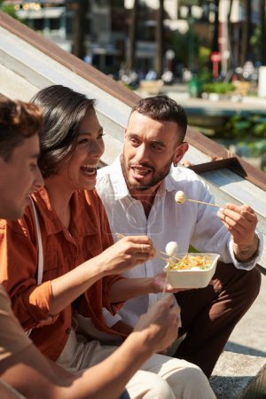 Téléchargez les photos : Heureux groupe d'amis manger de délicieux plats asiatiques de rue après avoir marché dans le parc - en image libre de droit
