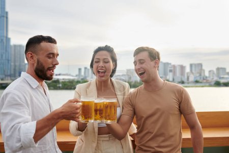 Téléchargez les photos : Groupe de jeunes gens s'amusant traîner et boire de la bière au restaurant bar sur le toit - en image libre de droit