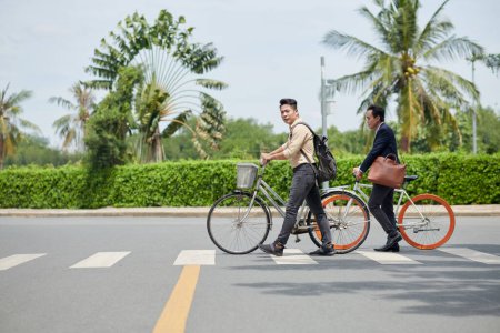 Téléchargez les photos : Citoyens avec vélos traversant la route sur un passage pour piétons - en image libre de droit
