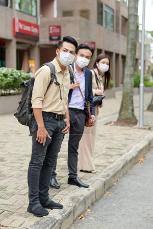 Photo for Group of businesss people in medical masks waiting for bus or taxi to go home after work - Royalty Free Image