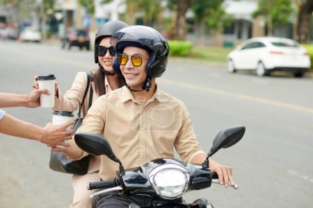 Téléchargez les photos : Couple d'affaires souriant sur scooter commander du café en voiture à travers le restaurant sur le chemin du travail - en image libre de droit
