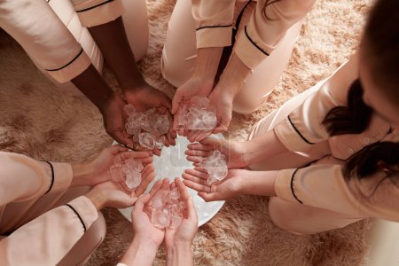 Photo for Group of young women putting ice cubes in big plate for magic ritual, view from above - Royalty Free Image