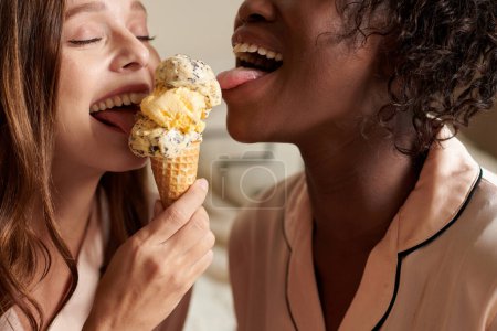 Photo for Cropped image of young women licking vanila and chocolate chip icecream - Royalty Free Image