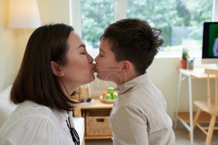 Téléchargez les photos : Petit garçon embrassant mère sur les lèvres quand ils jouent dans la pépinière - en image libre de droit