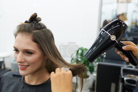 Téléchargez les photos : Coiffeur souffler les cheveux de séchage du client féminin - en image libre de droit