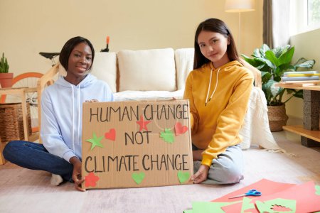 Téléchargez les photos : Des militants souriants montrant une pancarte qu'ils ont faite pour un événement sur le changement climatique au collège - en image libre de droit