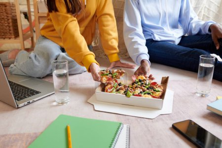 Foto de Estudiantes comiendo pizza suprema después de terminar la preparación para la prueba en línea - Imagen libre de derechos