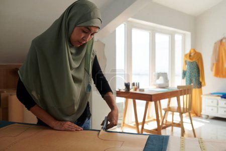 Téléchargez les photos : Couturière musulmane découpant motif de couture dans son atelier - en image libre de droit