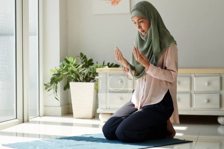 Foto de Religiosa musulmana madura mujer en hijab orando en casa - Imagen libre de derechos
