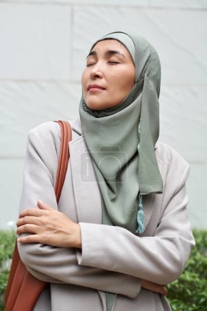 Photo for Portrait of muslim businesswoman in hijab standing outdoors, crossing arms and enjoying fresh air - Royalty Free Image