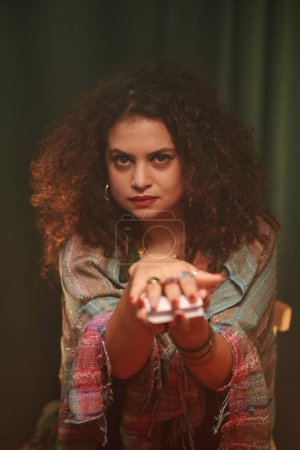 Photo for Portrait of serious fortune teller asking client to take tarot card from her hands - Royalty Free Image