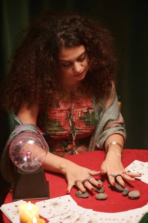 Foto de Vidente poniendo runas en la mesa con cartas del tarot propagación - Imagen libre de derechos