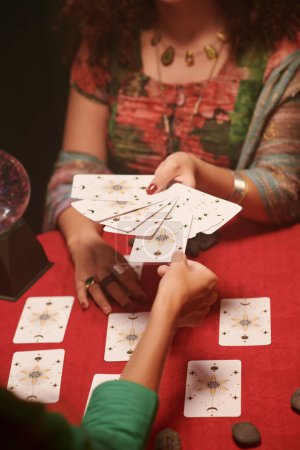 Frau stellt Frage und nimmt Tarotkarte aus Auslage