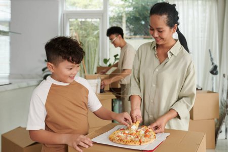 Foto de Familia hambrienta comiendo pizza después de empacar - Imagen libre de derechos