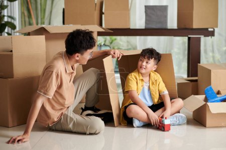 Photo for Preteen boy and his father playing together in new apartment after unpacking belongings - Royalty Free Image