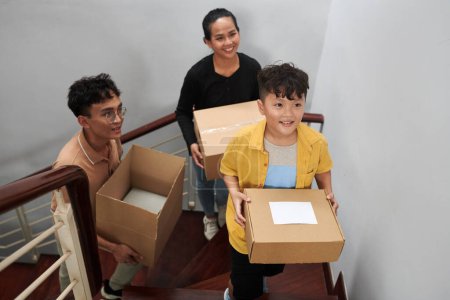 Foto de Familia feliz caminando arriba y llevando cajas con pertenencias a nuevo apartamento - Imagen libre de derechos