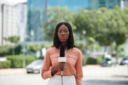 Téléchargez les photos : Portrait de journaliste noir sérieux parlant au microphone - en image libre de droit