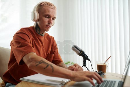 Photo for Serious podcaster setting program on laptop before recording voice - Royalty Free Image