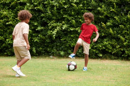 Foto de Niños disfrutando jugando al fútbol en el patio trasero en un día soleado - Imagen libre de derechos