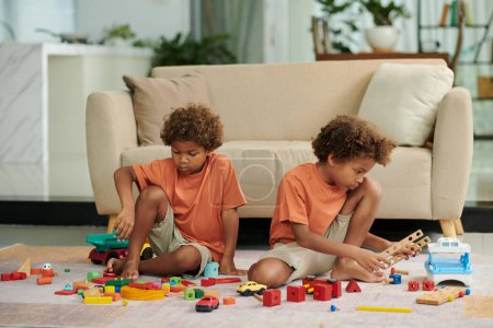 Foto de Hermanos serios jugando con juguetes en el suelo en la sala de estar - Imagen libre de derechos