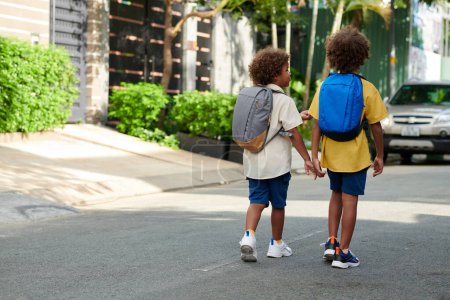 Téléchargez les photos : Enfants avec sacs à dos marchant jusqu'à l'école le matin - en image libre de droit