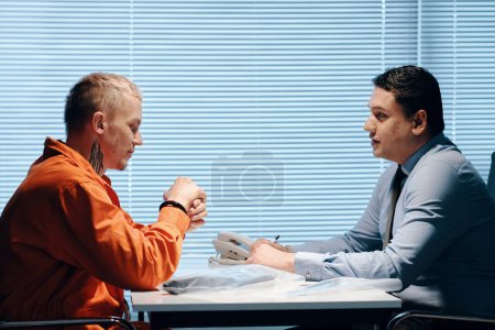 Téléchargez les photos : Inspecteur parlant à un meurtrier en uniforme orange lui demandant des détails sur le crime - en image libre de droit